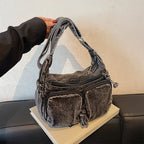 Denim shoulder bag with front pockets and buckle strap
